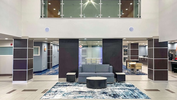A spacious lobby with a grey sofa, round coffee table, and a patterned rug. - Wingate by Wyndham Panama City Area Lynn Haven (Lynn Haven)