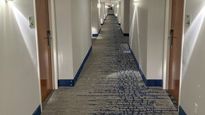 A long, narrow hotel corridor with carpeted floors and doors on both sides. - Wingate by Wyndham Panama City Area Lynn Haven (Lynn Haven)