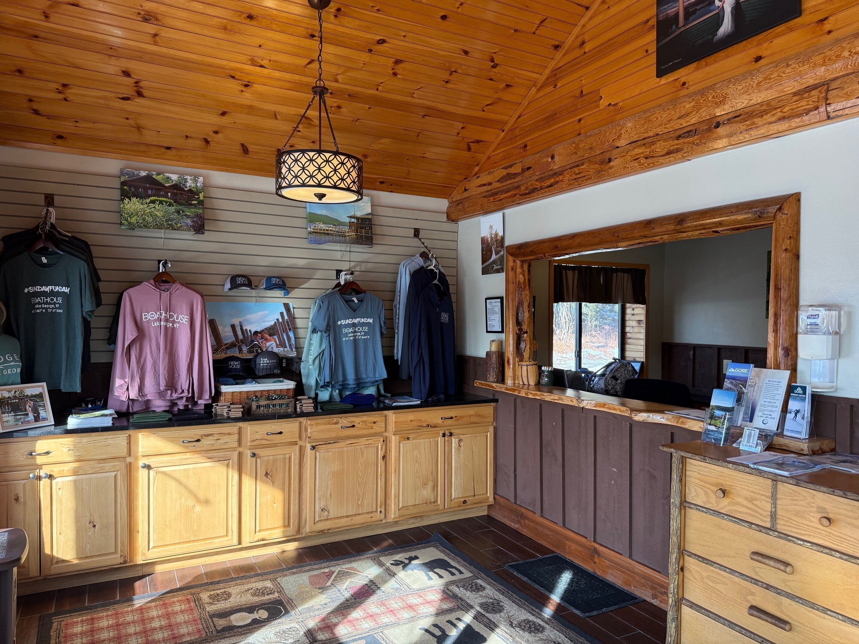 A wooden interior with a wooden ceiling, a hanging light fixture, and a counter displaying various items.