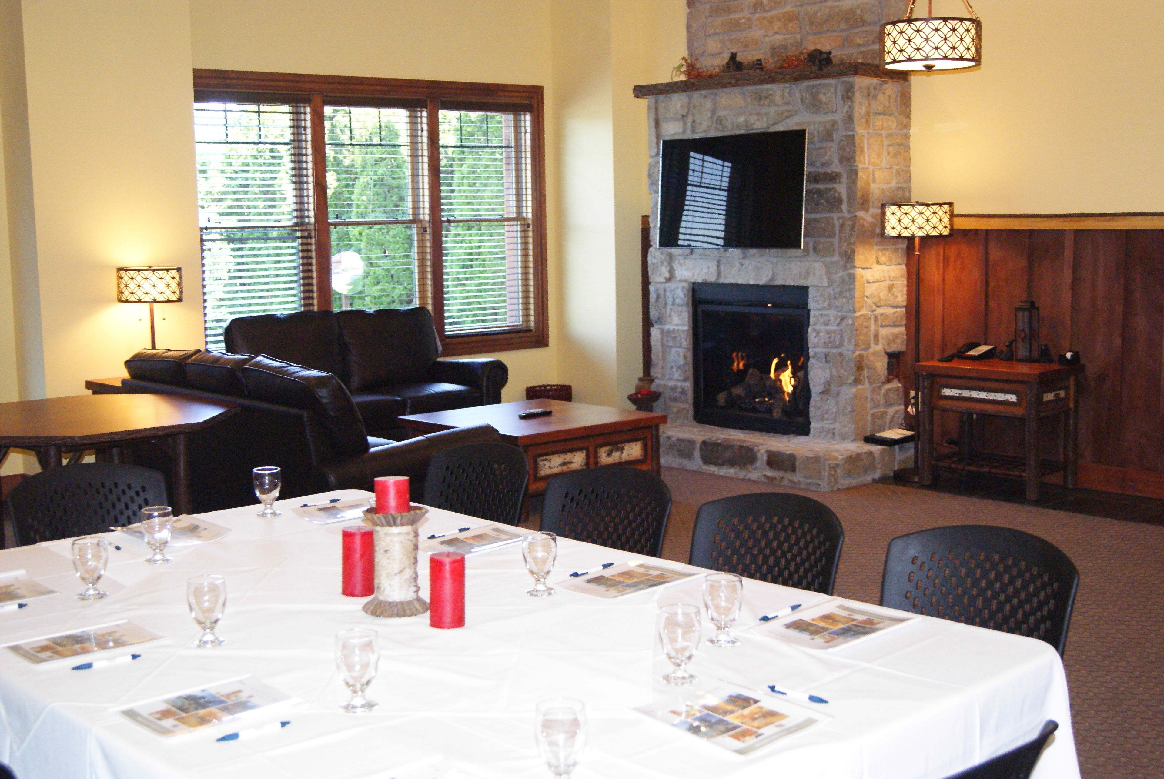 A dining area with a fireplace, a sofa, and a table set for a meal.