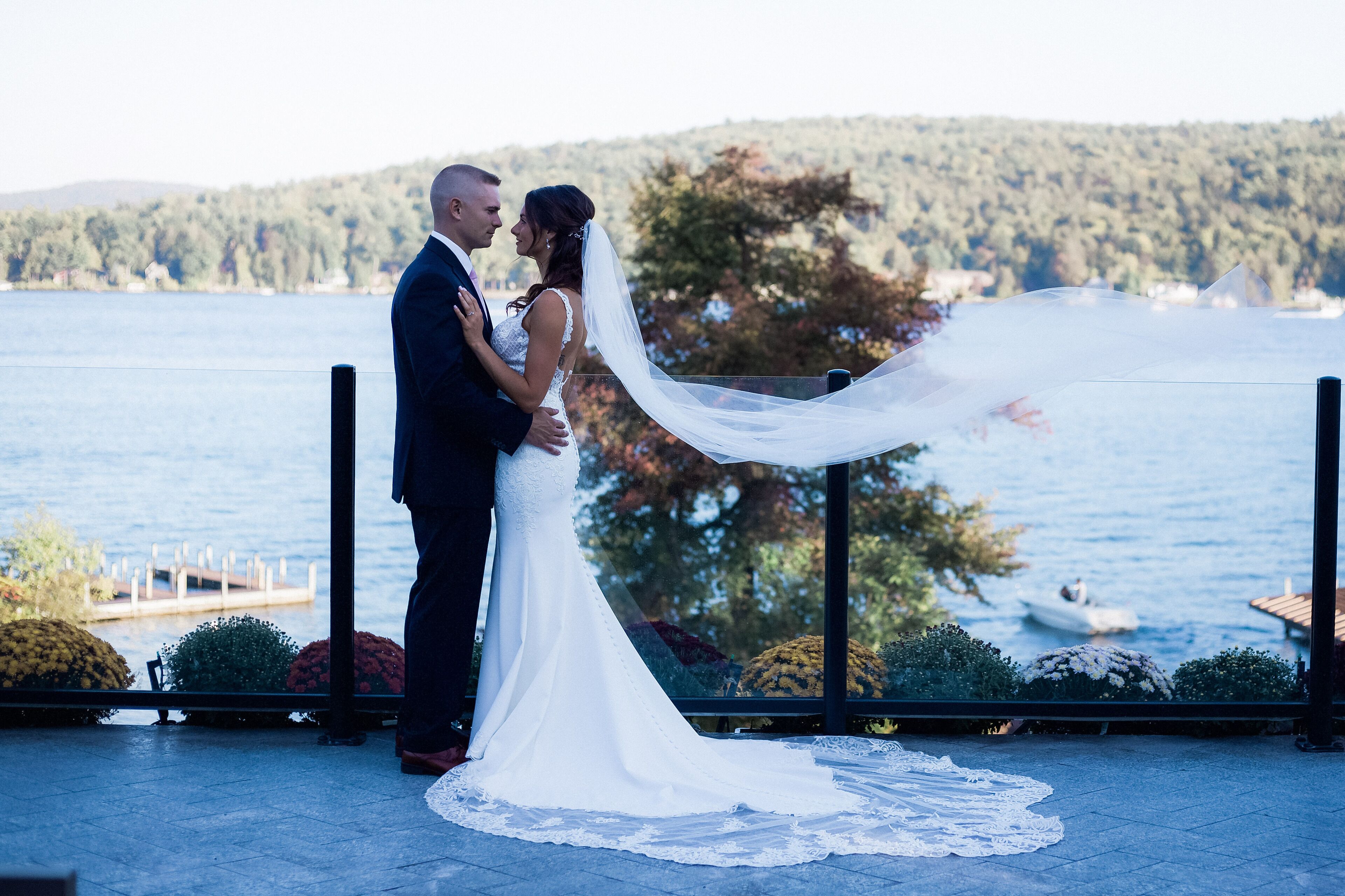 A couple embracing on a balcony with a lake view.