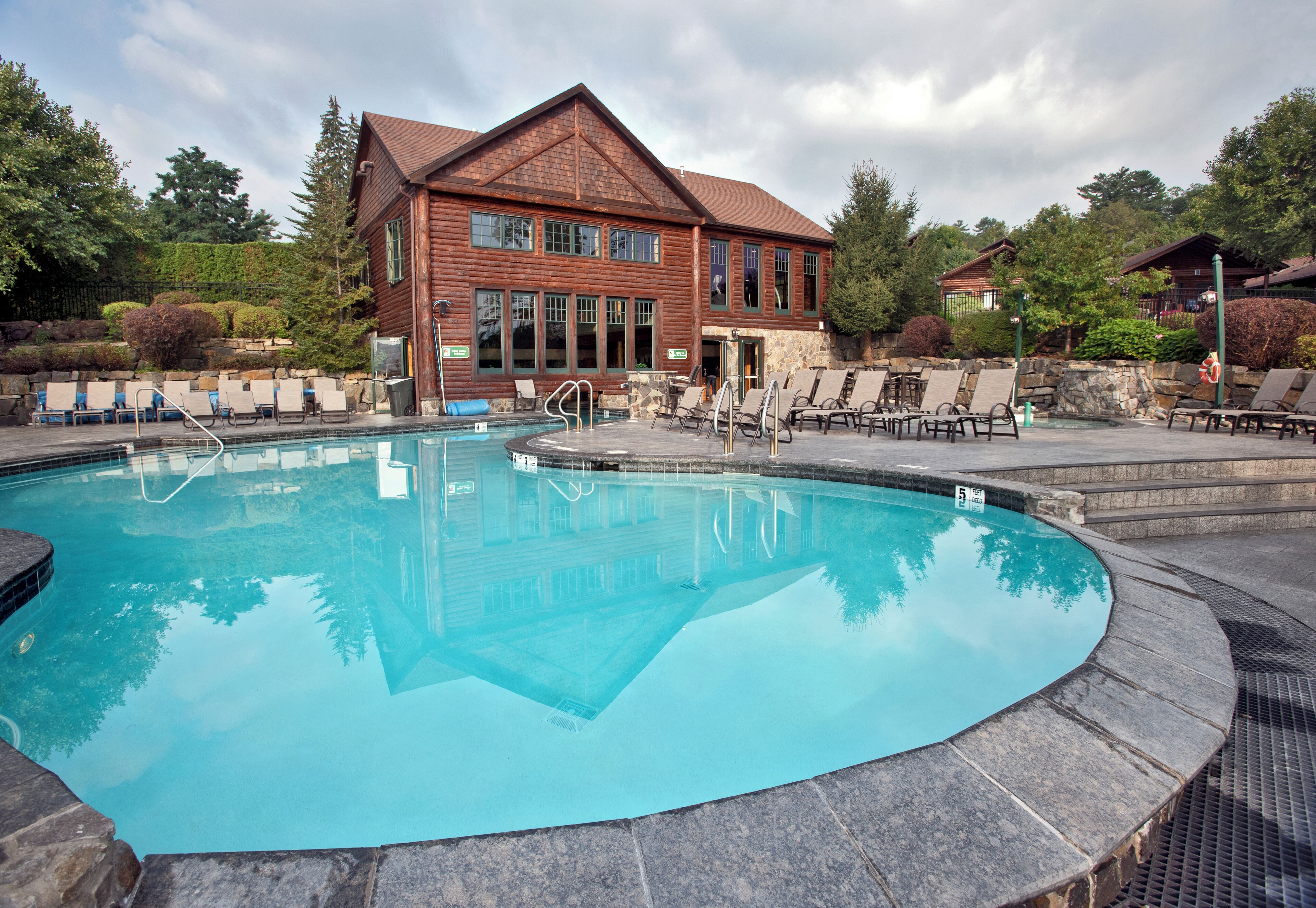 A swimming pool area with lounge chairs and a building in the background.