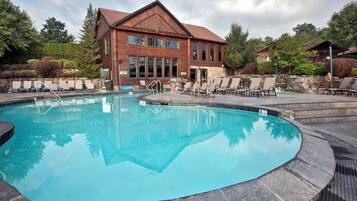 A swimming pool area with lounge chairs and a building in the background.