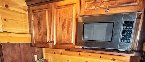 A kitchen with wooden cabinets, a granite countertop, a stainless steel microwave, a coffee maker, and a dishwasher.