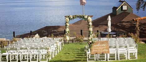 A lakeside wedding venue with rows of white chairs and a welcome sign.