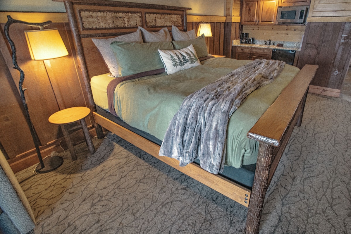 A wooden bed with a headboard, a bedside table, and a lamp.