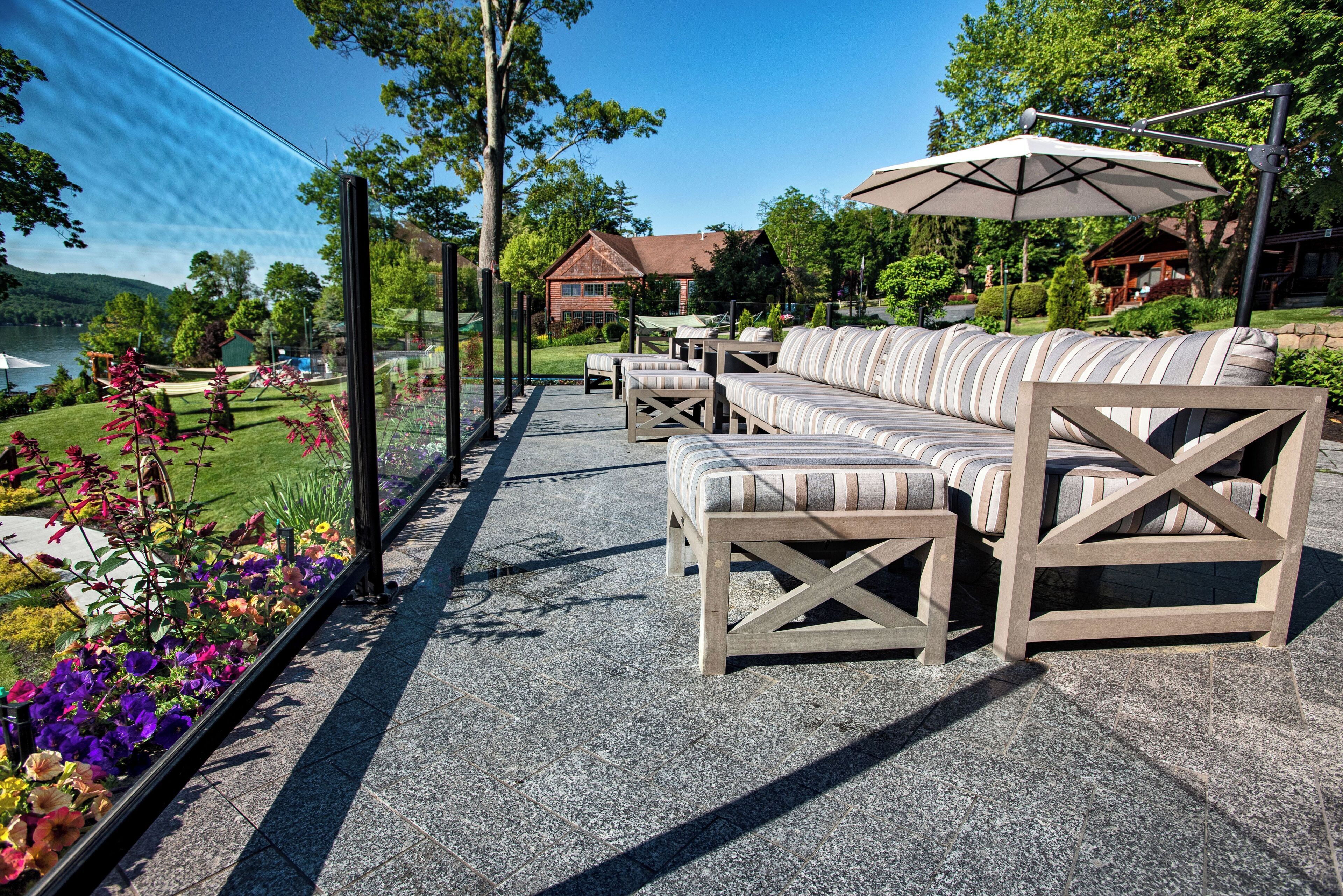 An outdoor seating area with a stone floor, cushioned sofas, and a large umbrella.
