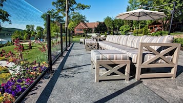 An outdoor seating area with a stone floor, cushioned sofas, and a large umbrella.