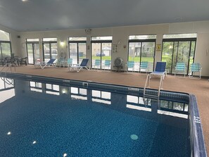 Una piscina interior con sillones de descanso y vistas al exterior.