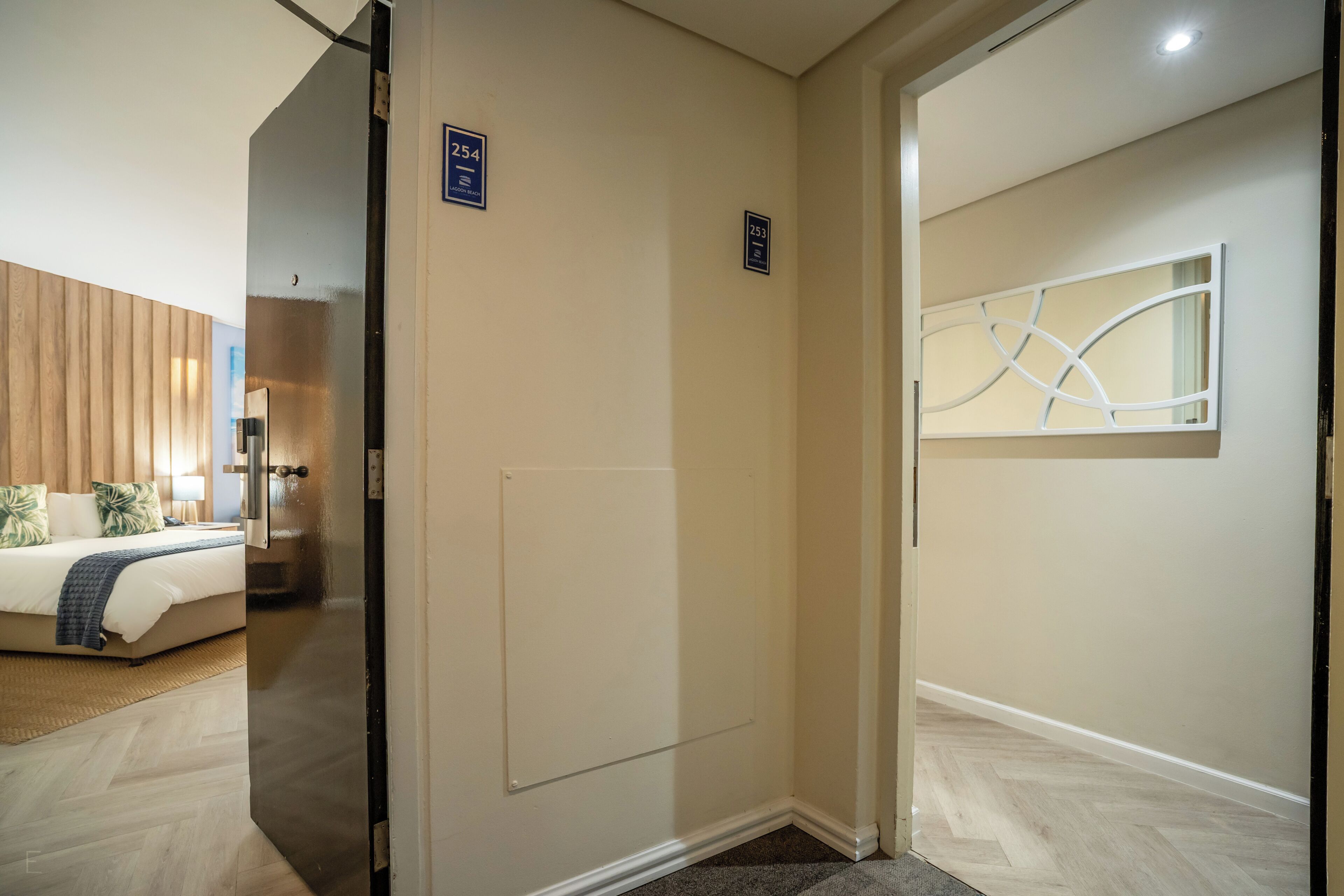 A hotel room with a bed, a nightstand, a lamp, and a wall-mounted artwork.