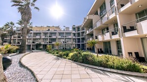 Un edificio moderno con varios balcones y un paseo pavimentado.