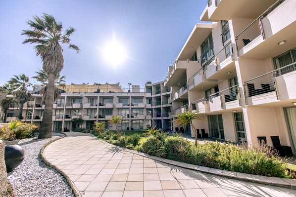 A modern building with multiple balconies and a paved walkway.