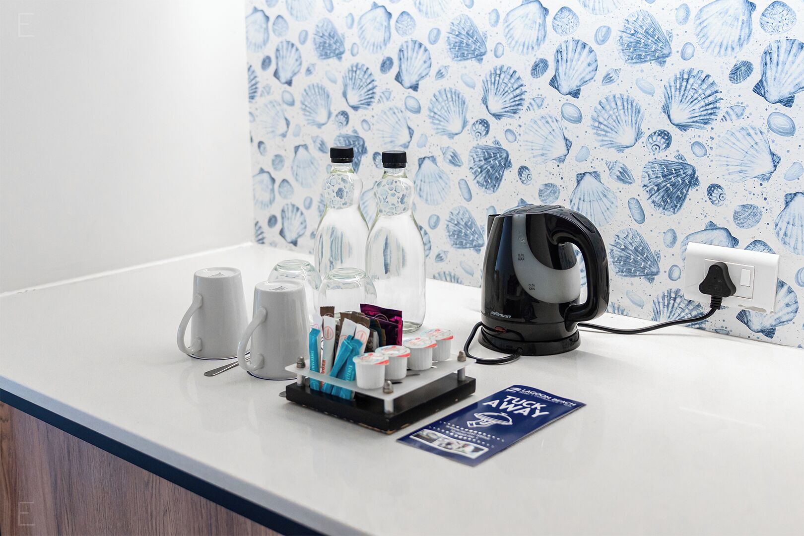 A kitchen counter with a kettle, bottles, and a coffee machine.