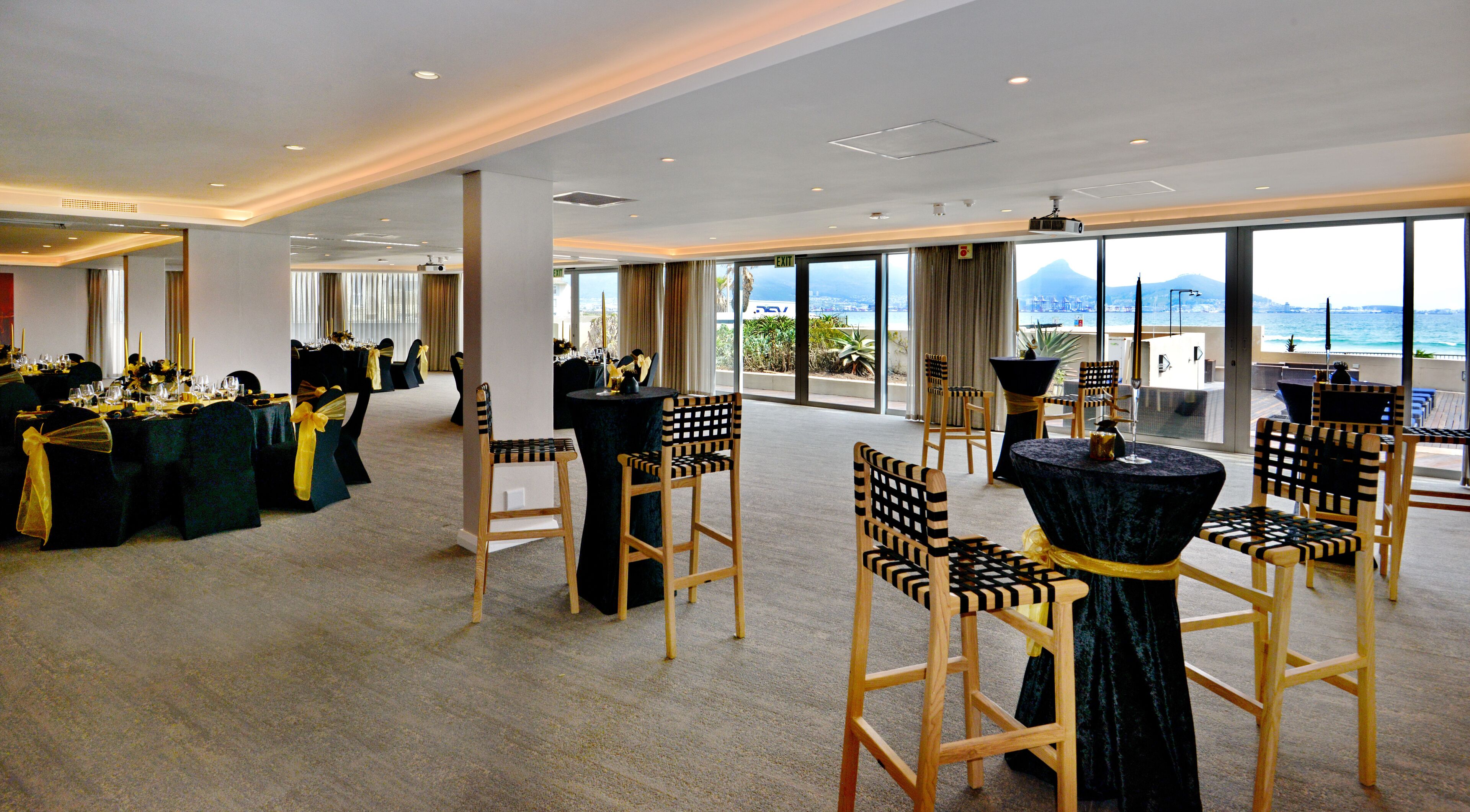 A spacious conference room with high ceilings and large windows offering a view of the ocean.