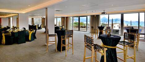 A spacious conference room with high ceilings and large windows offering a view of the ocean.