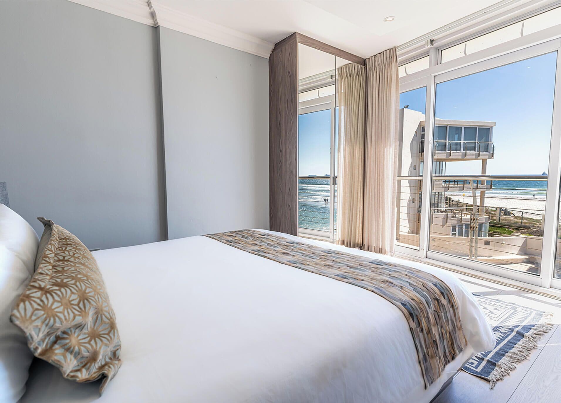 Quarto com uma cama grande, vista para a praia e uma torre salva-vidas.