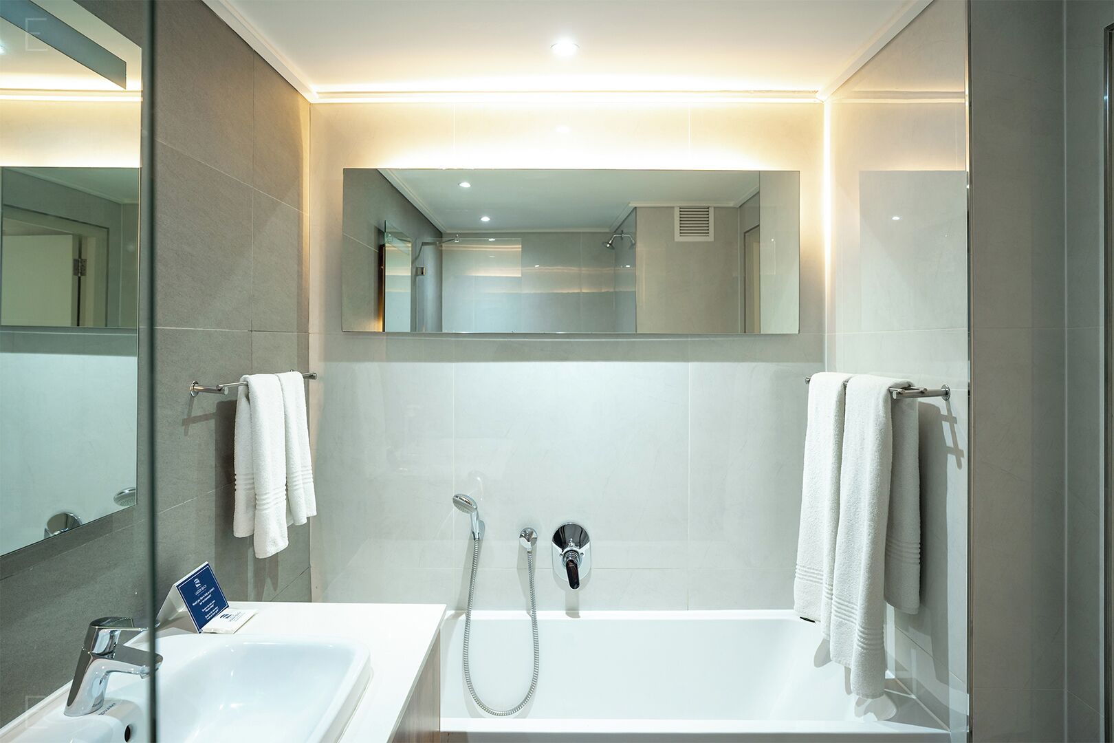 Un baño moderno con lavamanos doble, bañera y un espejo grande.