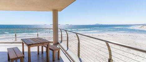 Un espacio de descanso techado con vista a la playa y al océano.