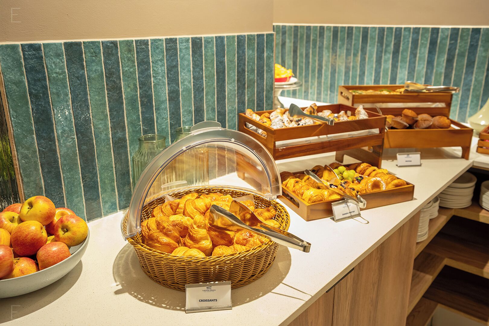 A buffet with various food items including croissants, fruits, and pastries.