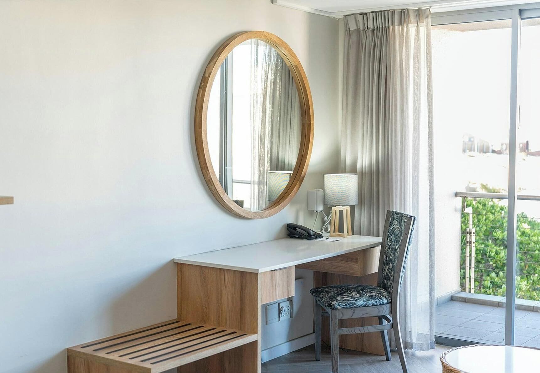 Une chambre d’hôtel équipée d’un bureau, d’une chaise et d’un grand miroir.