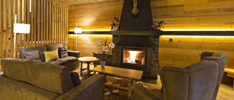 Una sala de estar acogedora con chimenea, paredes de madera y asientos cómodos.