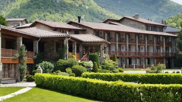 Un hôtel doté de nombreux balcons, de façades en pierre et surplombant un paysage montagneux.
