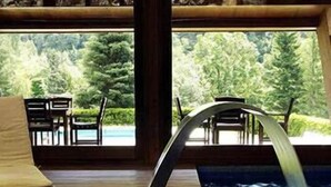 Une terrasse en bois avec une piscine, un fauteuil de relaxation et une vue sur une zone boisée.