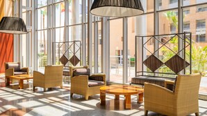 Un vestíbulo amplio con ventanas grandes, muebles de mimbre y una mesa redonda en el centro.