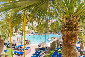 Un espace piscine avec des chaises longues et des palmiers.