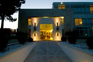A modern building entrance with a central pathway leading to a glass door, flanked by two light pillars. - Hotel MiraVillas (Mira)