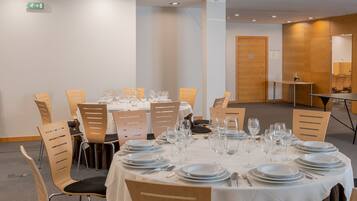 A conference room with round tables set for dining, equipped with chairs and dining essentials.