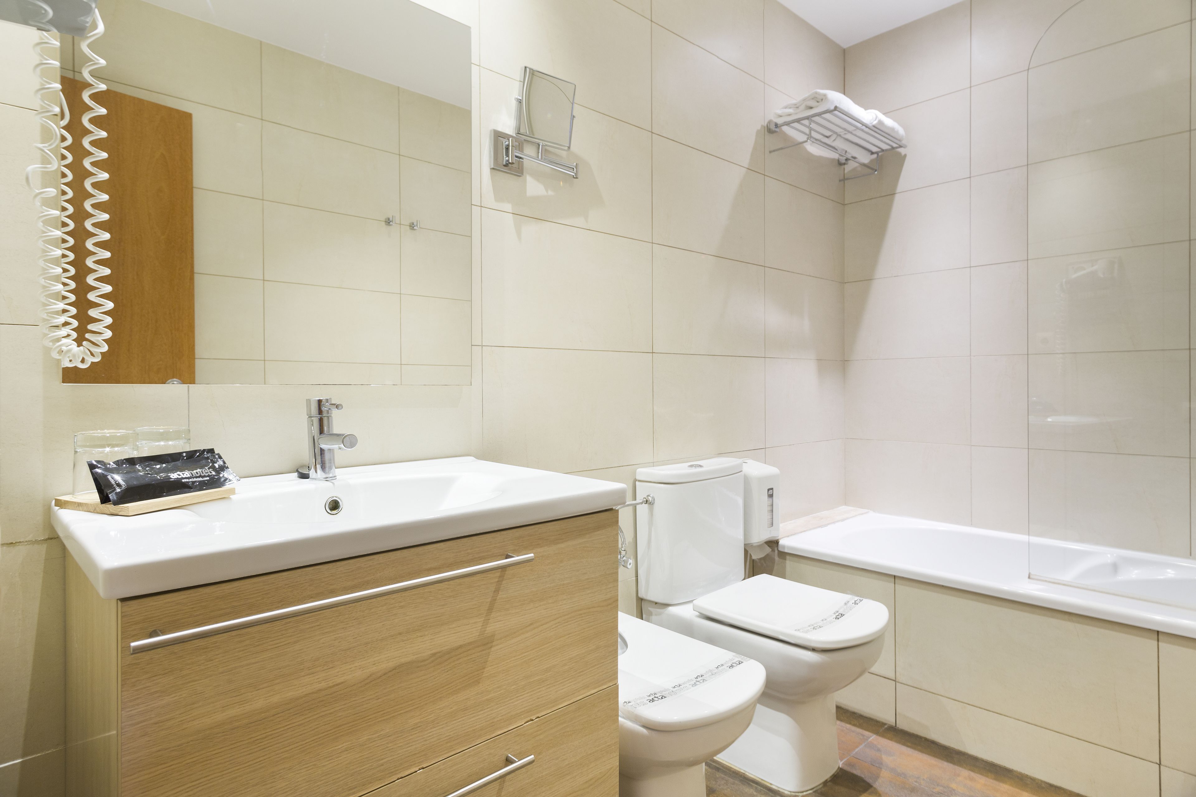 A modern bathroom with a sink, mirror, toilet, and bathtub.