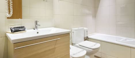 A modern bathroom with a sink, mirror, toilet, and bathtub.