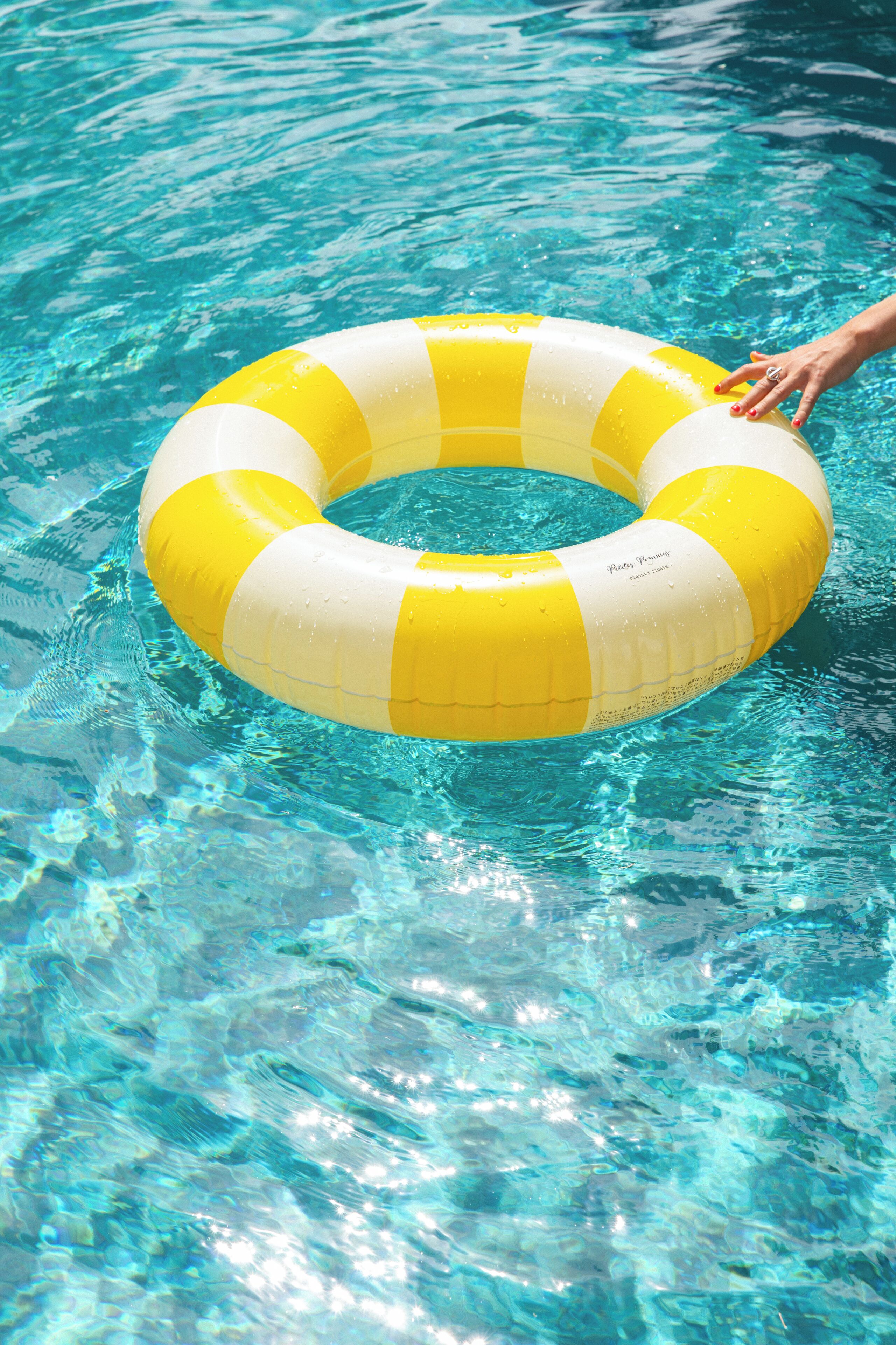 A yellow and white inflatable ring in a clear blue pool.