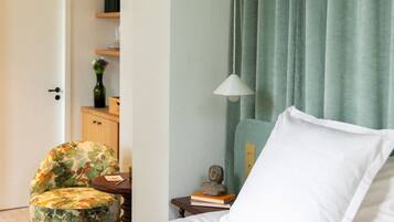 Een keurig opgemaakt slaapkamer met een bed, een stoel, een klein tafeltje en een lamp.
