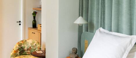 Une chambre bien rangée, avec un lit, une chaise, une petite table et une lampe.