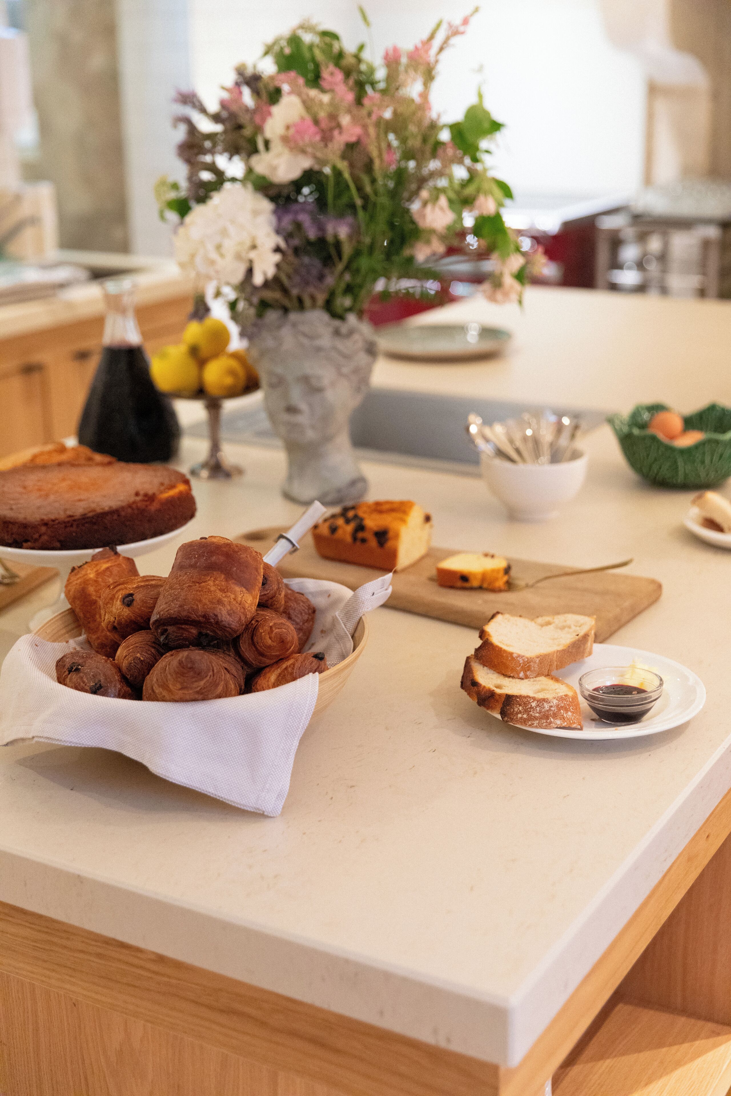 A kitchen counter with various baked goods, a vase of flowers, and kitchen utensils.