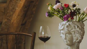 A wooden table with a vase of flowers, a wine glass, and a book.