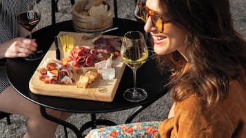 Una persona sentada en una mesa al aire libre, con diferentes platos de comida y copas de vino.