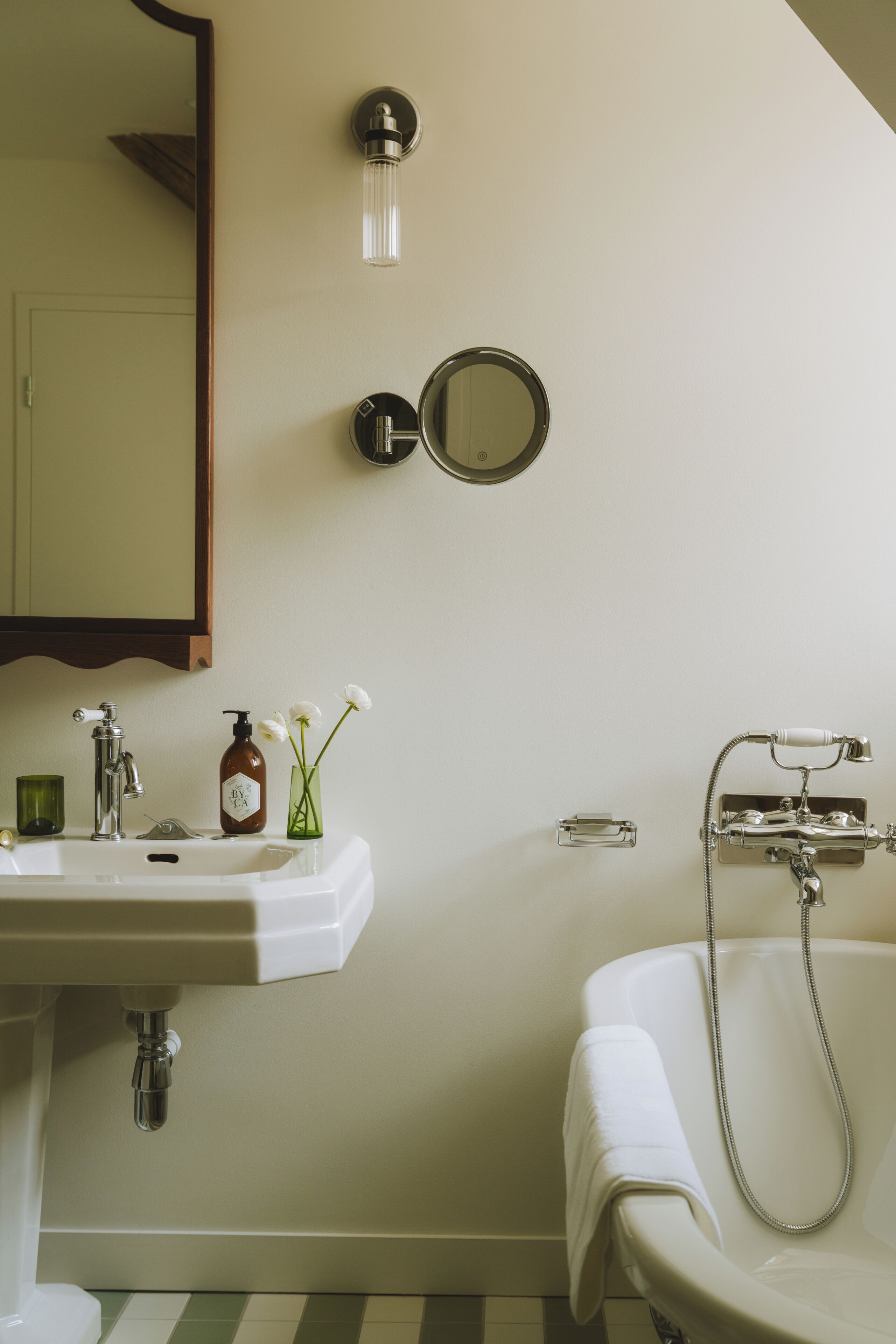 A bathroom with a sink, mirror, and bathtub.