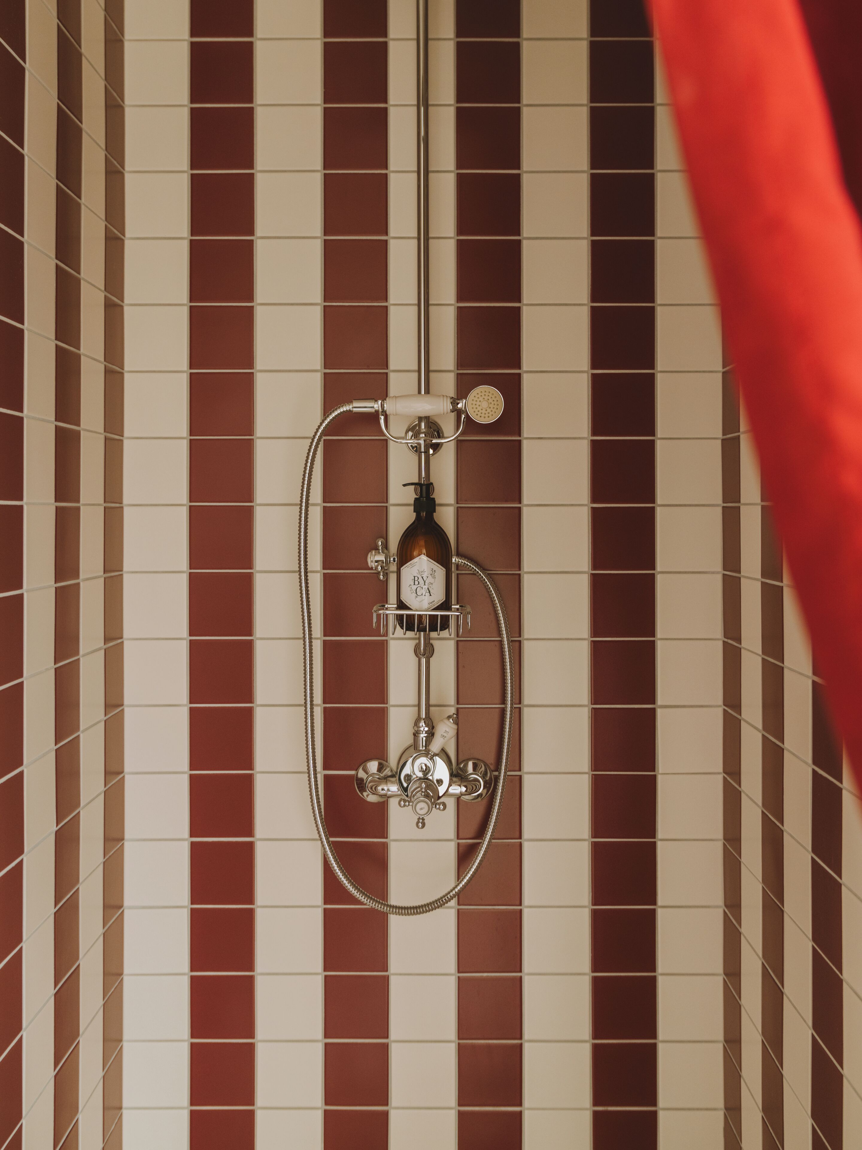 Une salle de bain avec un mur carrelé, une pomme de douche et un pommeau de douche amovible.