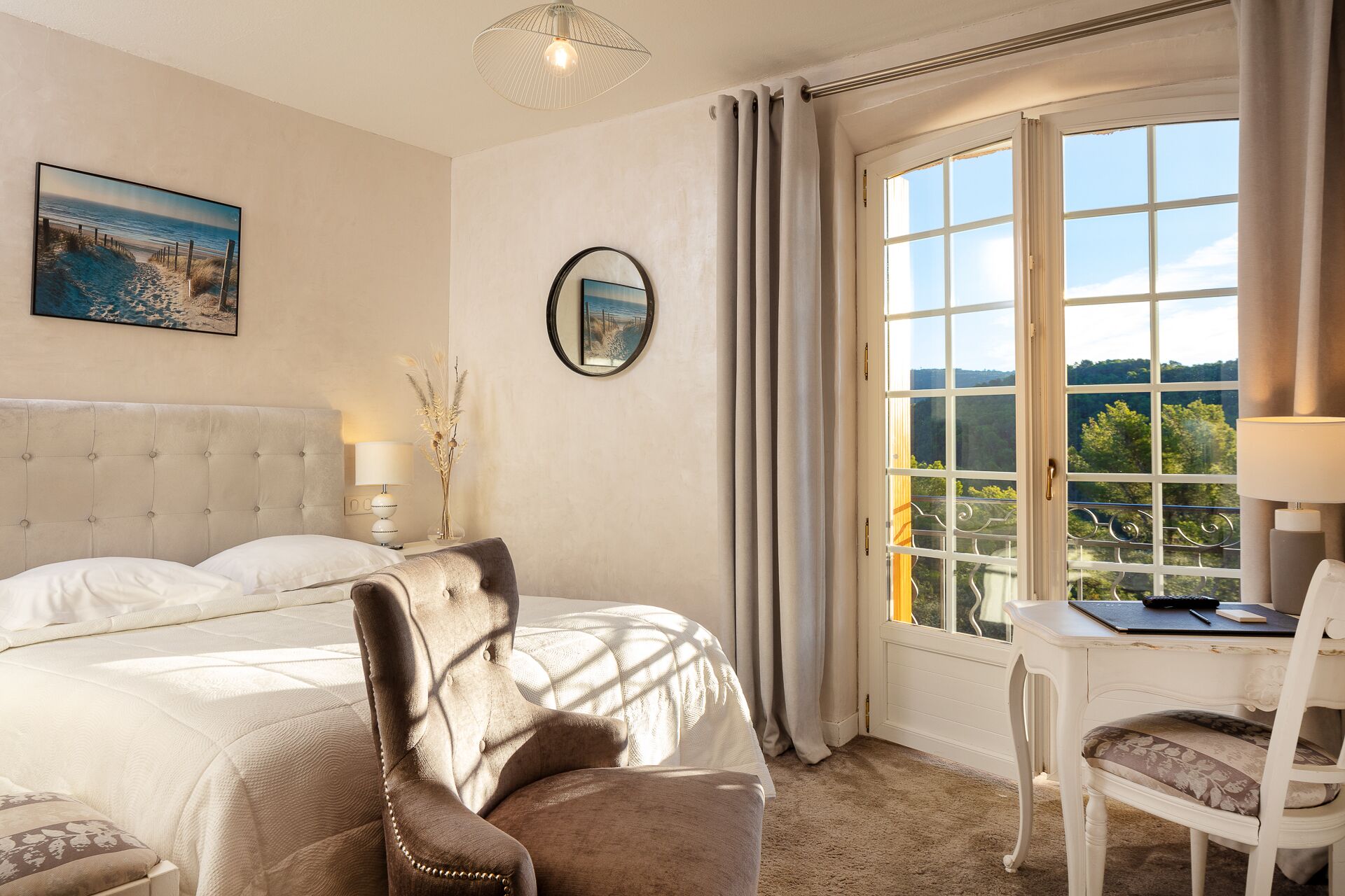 Un dormitorio con una cama grande, una silla, un escritorio y vistas al exterior a través de una ventana.