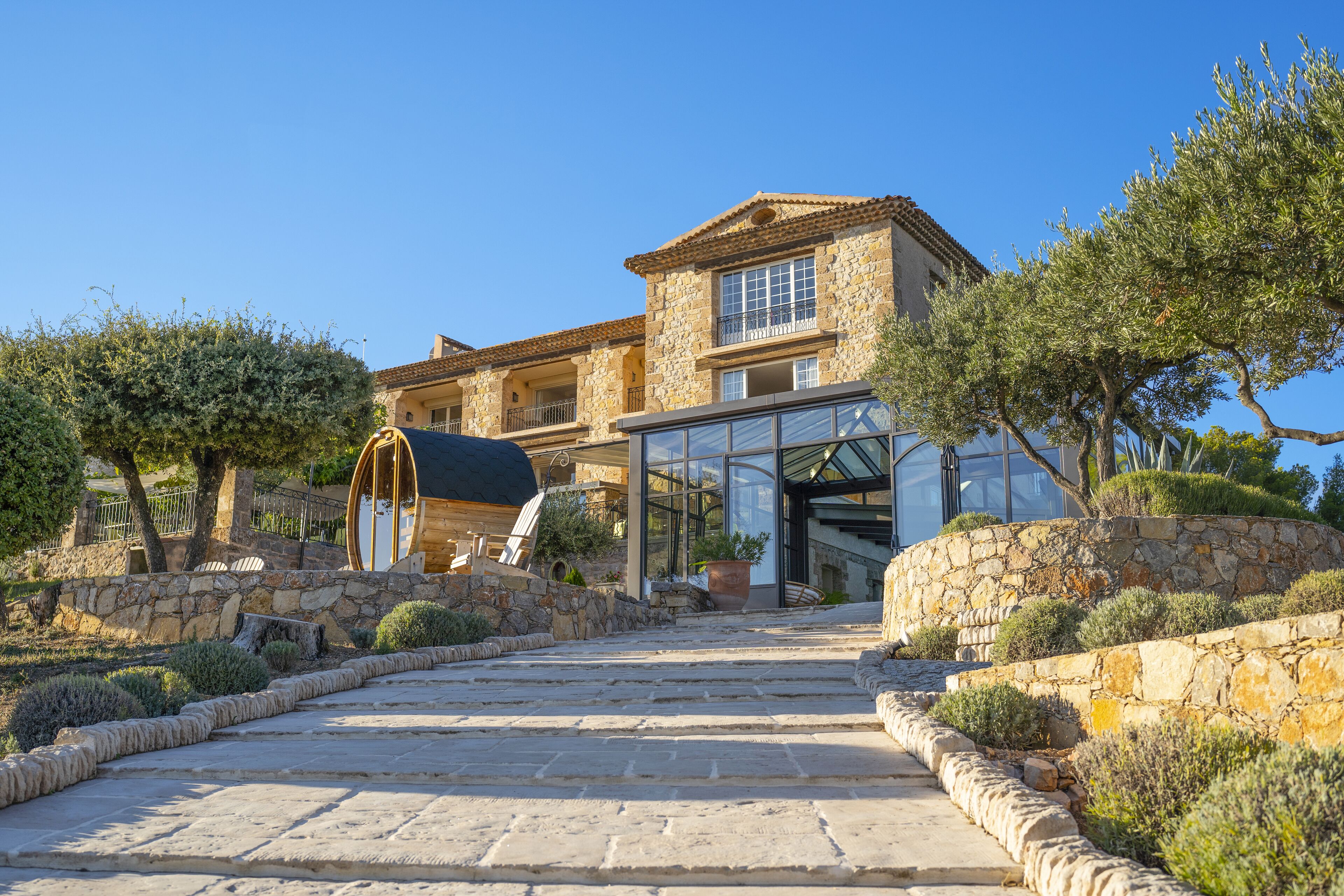 A stone building with a glass entrance, surrounded by stone walls and greenery.