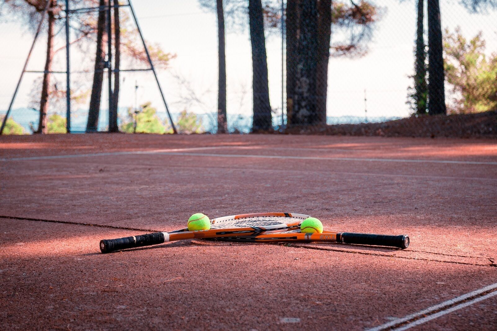 En tennisbane med ketcher og to tennisbolde.
