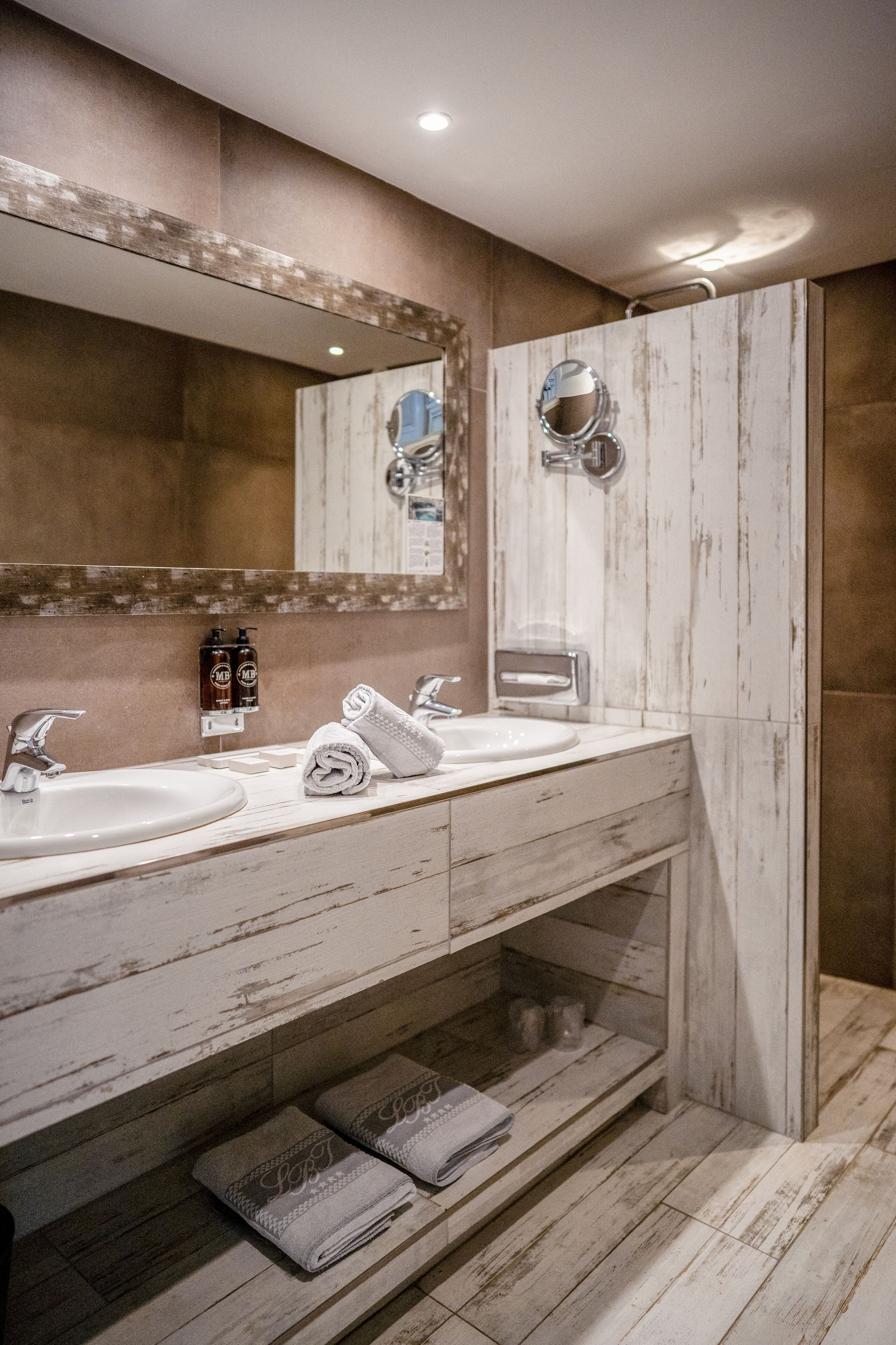 A bathroom with two sinks, a large mirror, and a shower area.