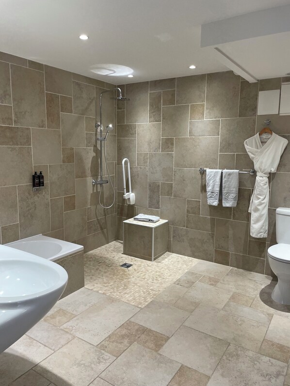A modern bathroom with a bathtub, toilet, and shower area.