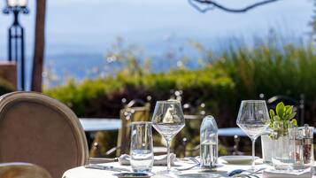 A table set for dining with clear glassware and a view of the sea in the background.