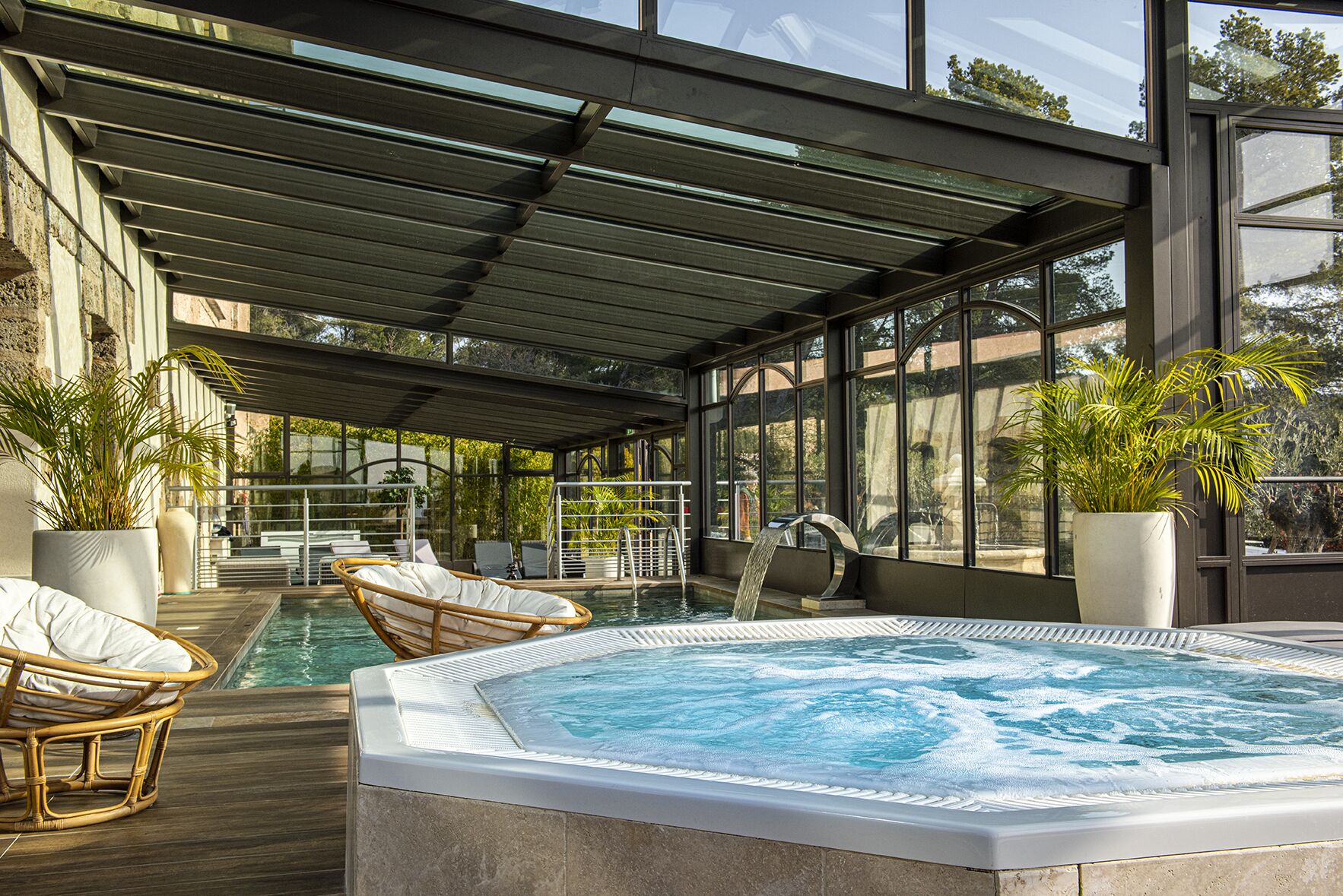 Un espace piscine doté d’un jacuzzi, de chaises longues et de plantes en pot.
