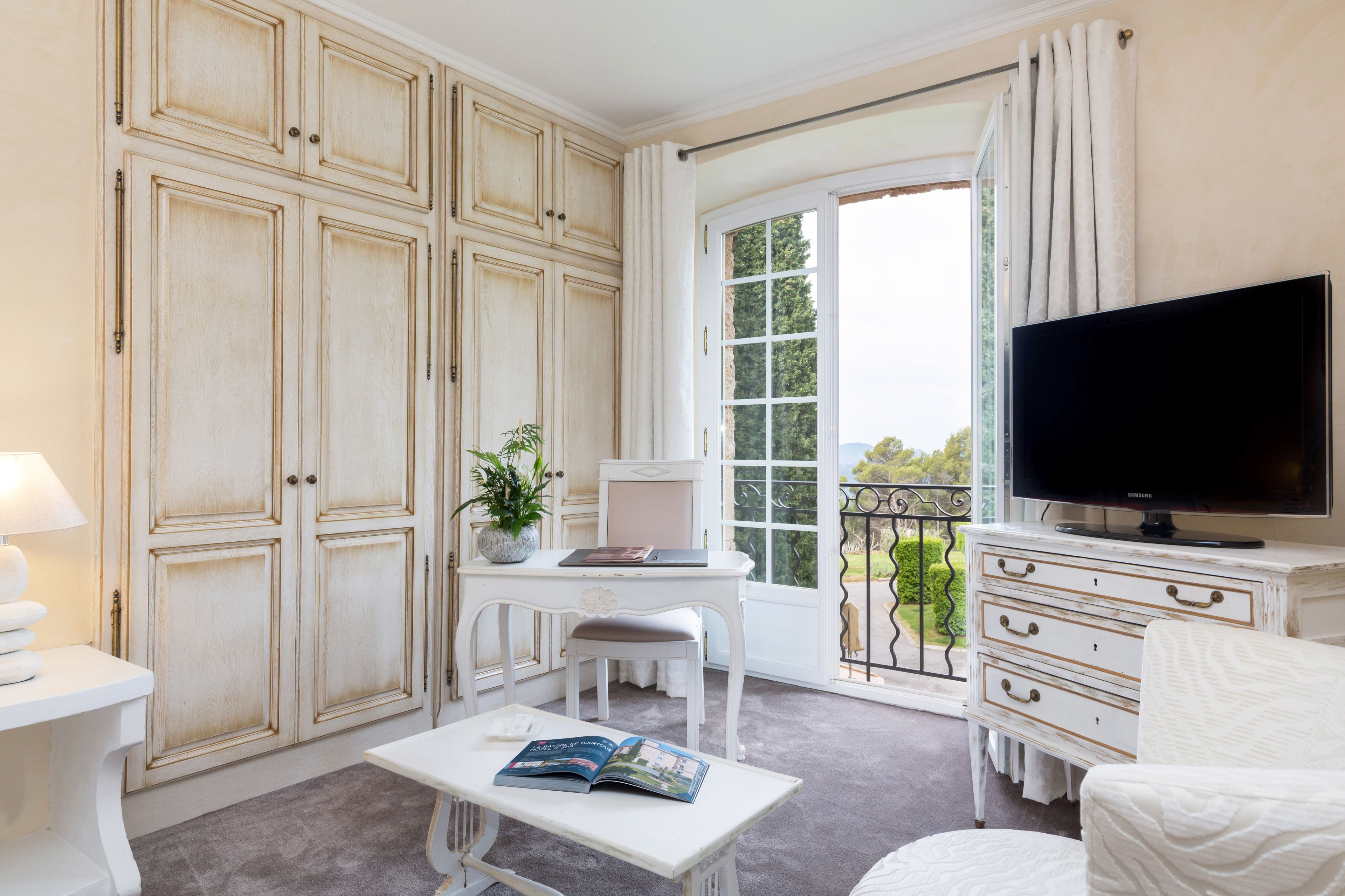A room with a large window, a television, a desk, and a chair.