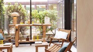 Ein moderner Außenbereich mit Holzmöbeln und einer Glaswand, die einen Blick auf den Garten bietet.